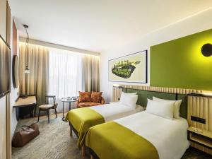 a hotel room with two beds and a chair at Mercure Katowice Centrum in Katowice