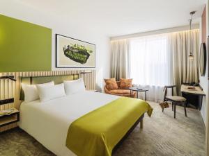 a hotel room with a large bed and a desk at Mercure Katowice Centrum in Katowice