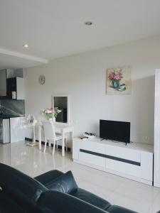 a white living room with a couch and a tv at 10 minutes to reach the karon beach, with free swimming pool and gym, WIFI in Karon Beach