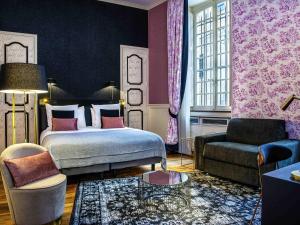 a bedroom with a bed and a couch and a chair at Mercure Figeac Viguier du Roy in Figeac