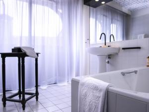 a white bathroom with a sink and a tub and a sink at Mercure Figeac Viguier du Roy in Figeac +91 photos