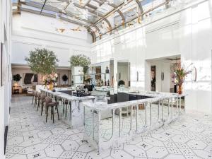 ラバトにあるFairmont La Marina Rabat Sale Hotelの白い壁と天井、テーブルと椅子のある広い部屋