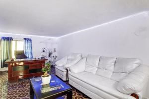 a living room with a white couch and a piano at Hotel O A Delight Residency in Surūrnagar