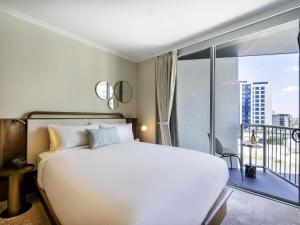 a bedroom with a large white bed and a balcony at Mantra Terrace Brisbane in Brisbane