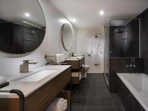 a bathroom with two sinks and a tub and a mirror at Mantra Terrace Brisbane in Brisbane