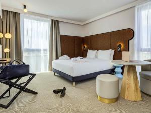 a hotel room with a large bed and a chair at Mercure Dunkerque Centre Gare in Dunkerque