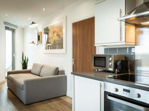 a kitchen and living room with a couch and a microwave at Aparthotel Adagio London Brentford in Brentford