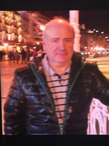 a man in a leather jacket standing on a city street at Car in Potosí