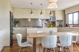 a kitchen with a wooden table and white chairs at The Majestic Coolum Ocean Views & Poolside Escape in Coolum Beach