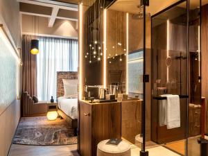 a bathroom with a shower and a bedroom with a bed at The Emporium Hotel Plovdiv - MGallery Collection in Plovdiv