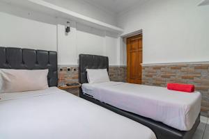 two beds sitting next to each other in a room at Wisma Vandera Syariah Garut Mitra RedDoorz in Garut