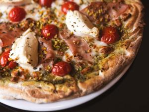 eine Pizza mit Tomaten und Käse auf einem Teller in der Unterkunft Mercure St. Julian's Malta in St Julian's
