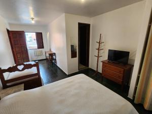 a bedroom with a bed and a dresser and a television at Pousada Bartrô in Rio das Ostras