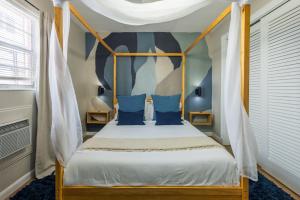 a bedroom with a canopy bed with blue pillows at Biva Luxe in West Palm Beach