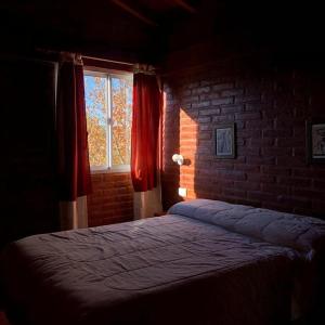 a bedroom with a bed with a brick wall and a window at Cabañas Gemas del Lago in Potrero de los Funes +38 photos