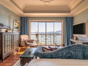 a living room with a couch and a large window at Raffles Udaipur in Udaipur