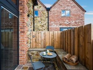 un patio con tavolo, sedie e una recinzione di Shropshire Way Stay a Farden
