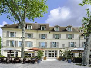 un grande edificio bianco con tavoli e sedie di Mercure Rambouillet Relays Du Château a Rambouillet