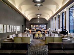 a lobby with couches and a bar with a piano at Sofitel Melbourne On Collins in Melbourne
