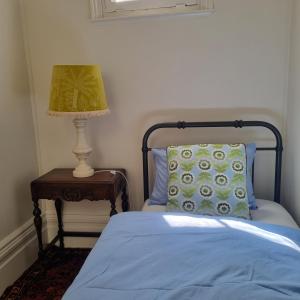 ein Schlafzimmer mit einem Bett und einer Lampe auf einem Tisch in der Unterkunft Ballarat Heritage Retreat in Nerrina
