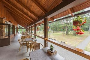 a patio with tables and chairs and a large window at ORO Dubingiai in Giraičiai 