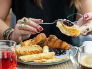 a woman eating a piece of bread and pastries on a plate at Novotel Rouen Sud Zenith Parc Expo in Saint-Étienne-du-Rouvray