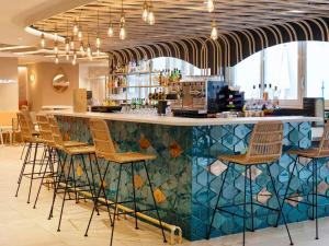 a bar in a restaurant with a mosaic wall at Novotel Montpellier in Montpellier