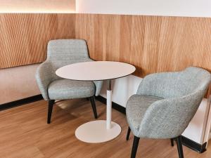 Dos sillas y una mesa blanca en una habitación. en Novotel Montpellier, en Montpellier 289 fotos más