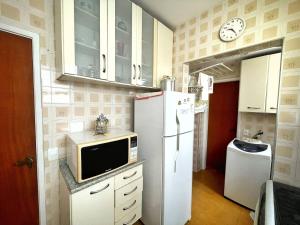 eine Küche mit Kühlschrank und Mikrowelle in der Unterkunft Apartamento 2 Quadras da Praia da Enseada in Guarujá