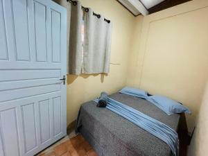 een kleine slaapkamer met een bed en een deur bij Chalé 2 em Ilhabela in Ilhabela