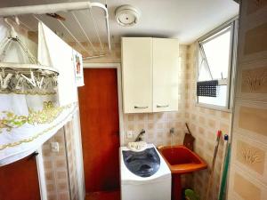 ein kleines Badezimmer mit Waschmaschine und Waschbecken in der Unterkunft Apartamento 2 Quadras da Praia da Enseada in Guarujá
