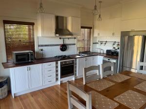 eine Küche mit weißen Schränken und einem Tisch mit Stühlen in der Unterkunft Peppergrove Cottage in Berry + 4 Fotos