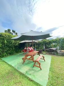 a picnic table and an umbrella on a green pad at Villa 99 Nabila Kayna Puncak in Paragajen