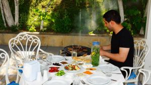 a man sitting at a table with food at River Side Hotel in Mingachevir
