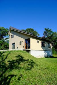 a house on top of a grassy hill at Meanwhile Woods in Myoko