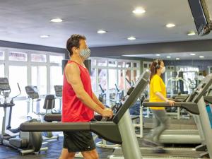 a man and woman in a gym on tread machines at Novotel Sao Jose dos Campos in São José dos Campos
