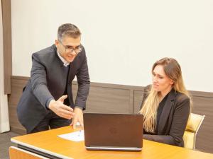 a man and a woman sitting at a table with a laptop at Novotel Sao Jose dos Campos in São José dos Campos