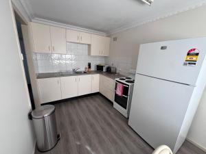 Una cocina con gabinetes blancos y un refrigerador blanco. en Apartments on Turf Unit 3, en Grafton 8 fotos más