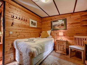 グラスミアにある2 Bed in Ambleside 75731の木製の壁のベッドルーム1室、ベッド1台、椅子が備わります。