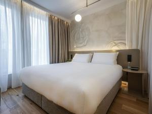 a large white bed in a room with windows at Maison Sofia - MGallery in Sofia