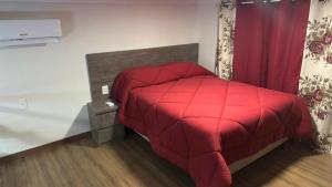 een rood bed met een rood dekbed in een kamer bij Loft Firenze - Conforto e Estilo na Serra Gaúcha in Bento Gonçalves