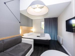 a hotel room with a bed and a couch at ibis Sisteron in Sisteron