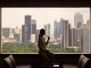 a woman sitting in a window drinking a glass of wine at Fairmont Jakarta in Jakarta