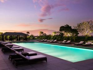 a swimming pool with lounge chairs and a gazebo at Fairmont Jakarta in Jakarta