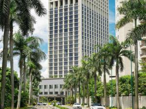 a tall building with palm trees in front of it at Fairmont Jakarta in Jakarta