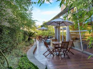 a wooden deck with chairs and tables with umbrellas at ibis budget Sao Paulo Paraiso in Sao Paulo