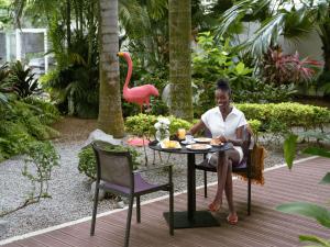 a woman sitting at a table in front of a pink flamingo at Novotel Abidjan Plateau in Abidjan
