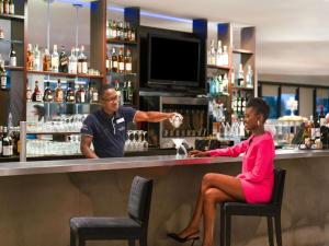a woman sitting at a bar with a bartender at Novotel Abidjan Plateau in Abidjan