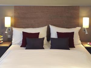 a large bed with red and white pillows at Mercure Hotel Frankfurt Eschborn Ost in Eschborn