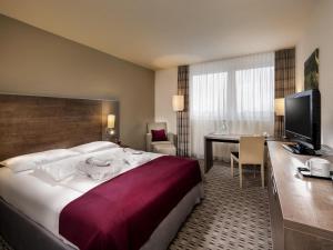 a hotel room with a large bed and a desk at Mercure Hotel Frankfurt Eschborn Ost in Eschborn +66 photos